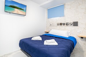 Quarto com cama, televisão na parede, janela e parede decorada.