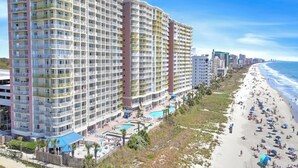 A high-rise hotel with multiple balconies, a pool area, and a beachside location. - Bay Watch Resort 1239 -Oceanfront-Water Amenities (North Myrtle Beach)