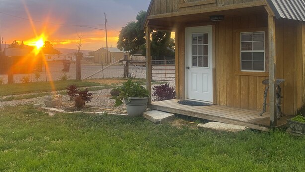 Una cabaña de madera con un porche, una puerta y una ventana.