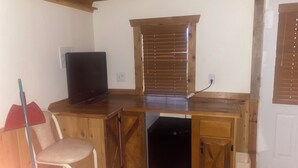 Una cocina compacta con encimera de madera, lavavajillas integrado y ventana con persianas.