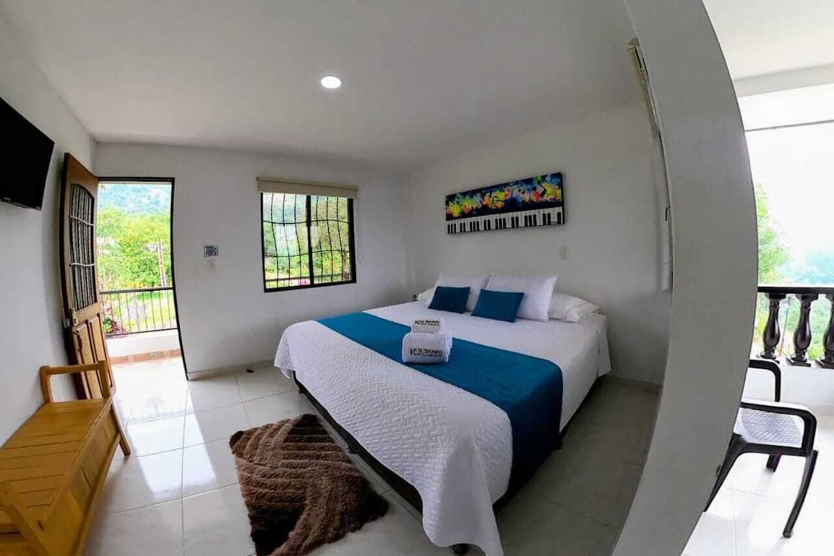 A bedroom with a bed, a window, a door, and a balcony.