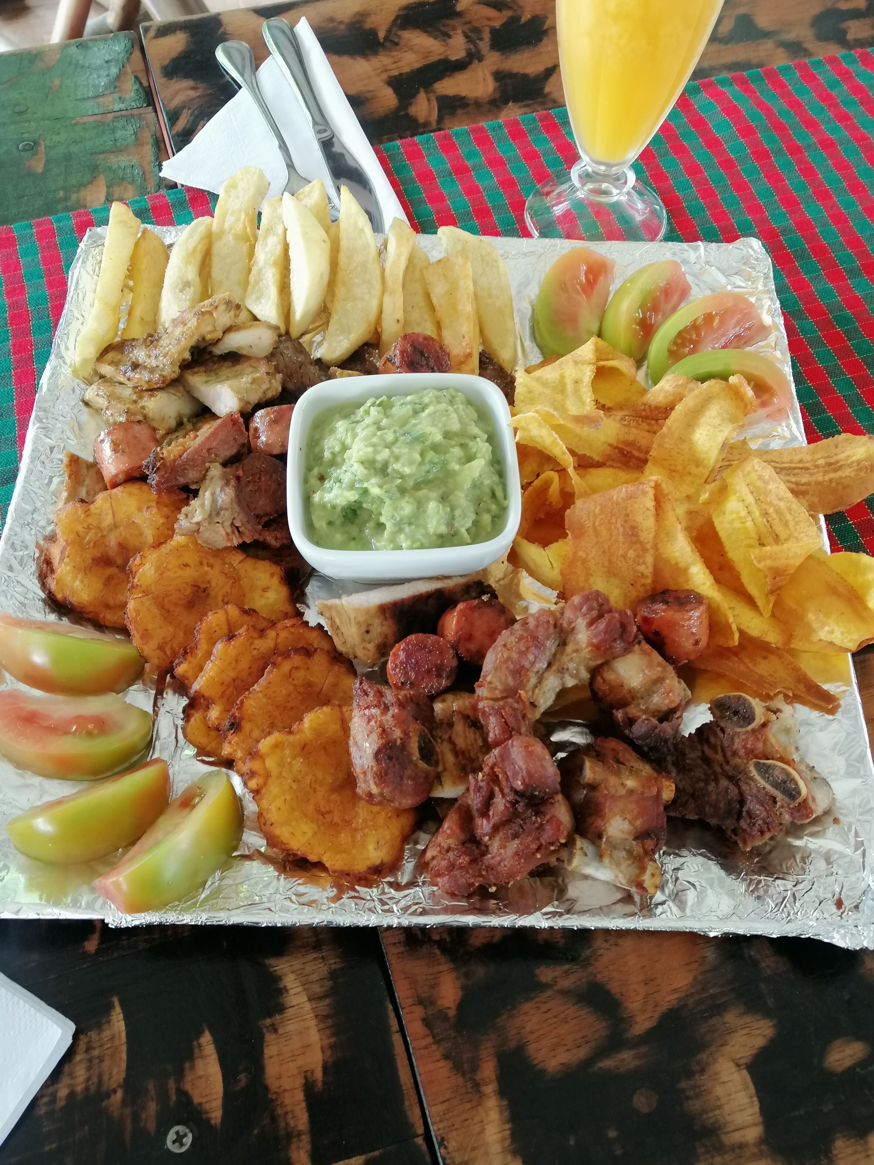 A meal with various fried items, a glass of orange juice, and a napkin on a table.