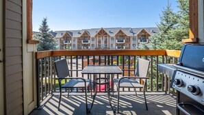 A balcony with a grill, two chairs, and a table. - Wild Horses | Pool | Hot Tub | Hot Springs (Radium Hot Springs)
