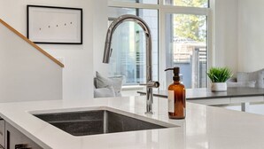 Cuina moderna amb taulell blanc, aixeta d'acer inoxidable i una ampolla de sabó.
