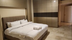 Ein Hotelzimmer mit einem großen Bett, einer Kopfteil, einem Kleiderschrank und einer Tür.