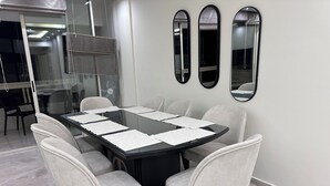 Ein Konferenzraum mit einem Glastisch, sechs Stühlen und drei Wandspiegeln.