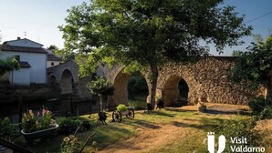 Un patio con arcos de piedra, un árbol y un edificio blanco.