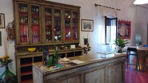 Zona de recepción con mostrador de madera, un armario con puertas de vidrio y una ventana con cortinas.