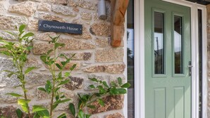 A stone wall with a sign reading "Chynoweth House" and a green door with a window. - Chynoweth House (Newquay)