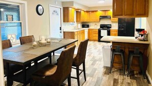 Une cuisine moderne avec des meubles en bois, un coin repas comprenant une table et des chaises, et un ventilateur de plafond.