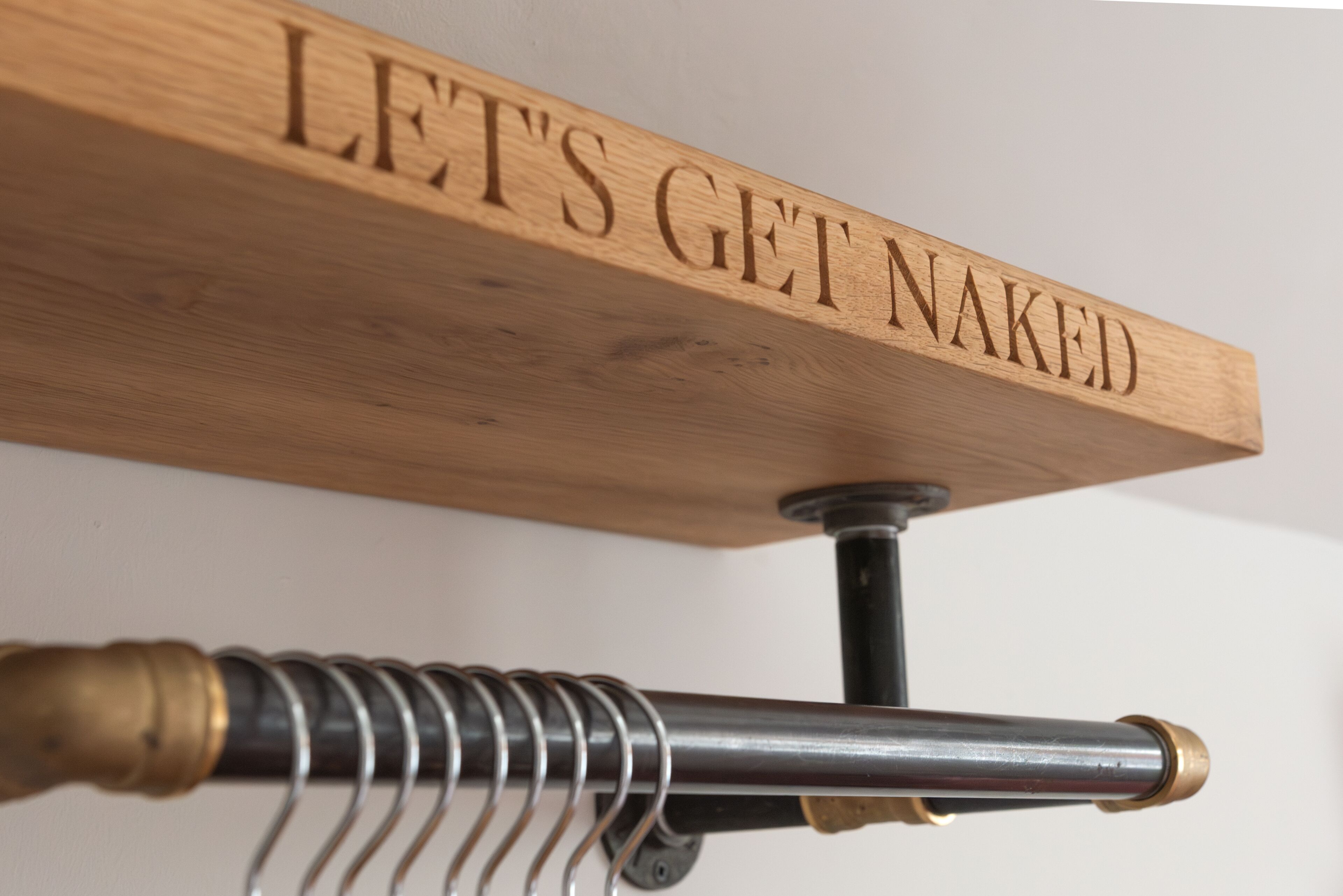 A wooden sign with the text "LET'S GET NAKED" mounted on a metal rod.