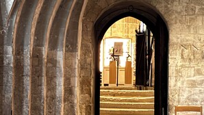 Una porta d'arc de pedra que dona a una escala de fusta.