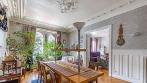 A dining area with a long wooden table, chairs, and a decorative floor lamp. - Sophisticated and Grand Apt. in Perfect Location! (Paris)