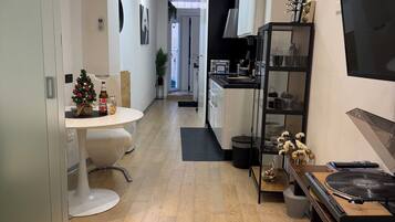 A modern kitchen with a black countertop, a wooden dining table, and a small Christmas tree.