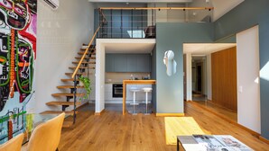 Un loft moderno con escalera de madera, cocina y comedor con taburetes de bar.