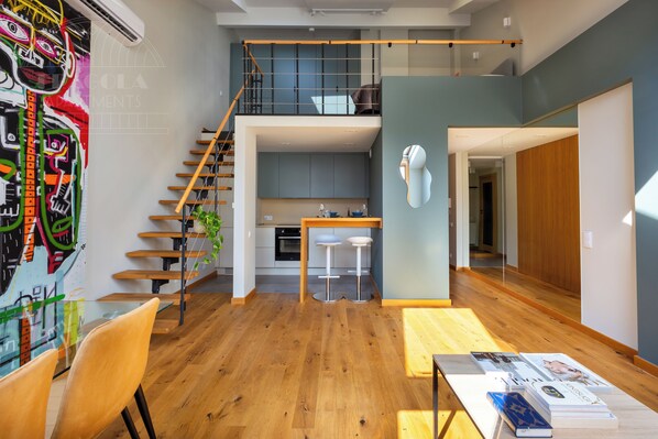 A modern loft apartment with a wooden staircase, a kitchen, and a dining area with bar stools. - ArtSquare by Fragola Apartments (Kraków)