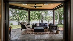 Un patio ouvert avec un ventilateur de plafond, un canapé, un fauteuil et une table basse.