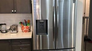 A stainless steel refrigerator in a kitchen with dark cabinets and a tiled backsplash. - Niagara Relaxing Getaway - La Maison de Niagara (Niagara Falls)