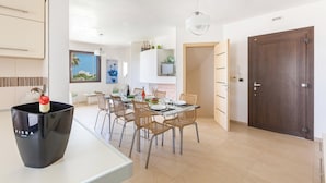 Une cuisine moderne avec un coin repas, comprenant une cafetière noire, des chaises en osier et une porte en bois.