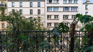 A multi-story residential building with balconies, a wrought iron fence, and lush greenery. - Central, Spacious Family Apartment with Balcony (Paris)