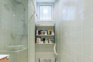 Ein Badezimmer mit Dusche, Toilette, Waschbecken und Ablage für Toilettenartikel.