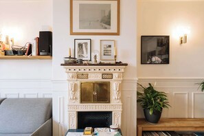 A living room with a fireplace, a sofa, a coffee table, and a bookshelf.