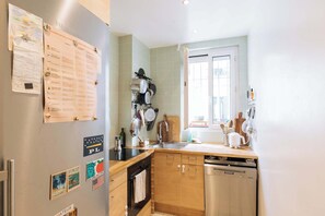 A kitchen with a refrigerator, stove, sink, and wooden cabinets. - Central, Spacious Family Apartment with Balcony (Paris)
