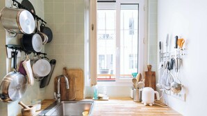 A kitchen with a wooden countertop, a sink, and various kitchen utensils and cookware. - Central, Spacious Family Apartment with Balcony (Paris)