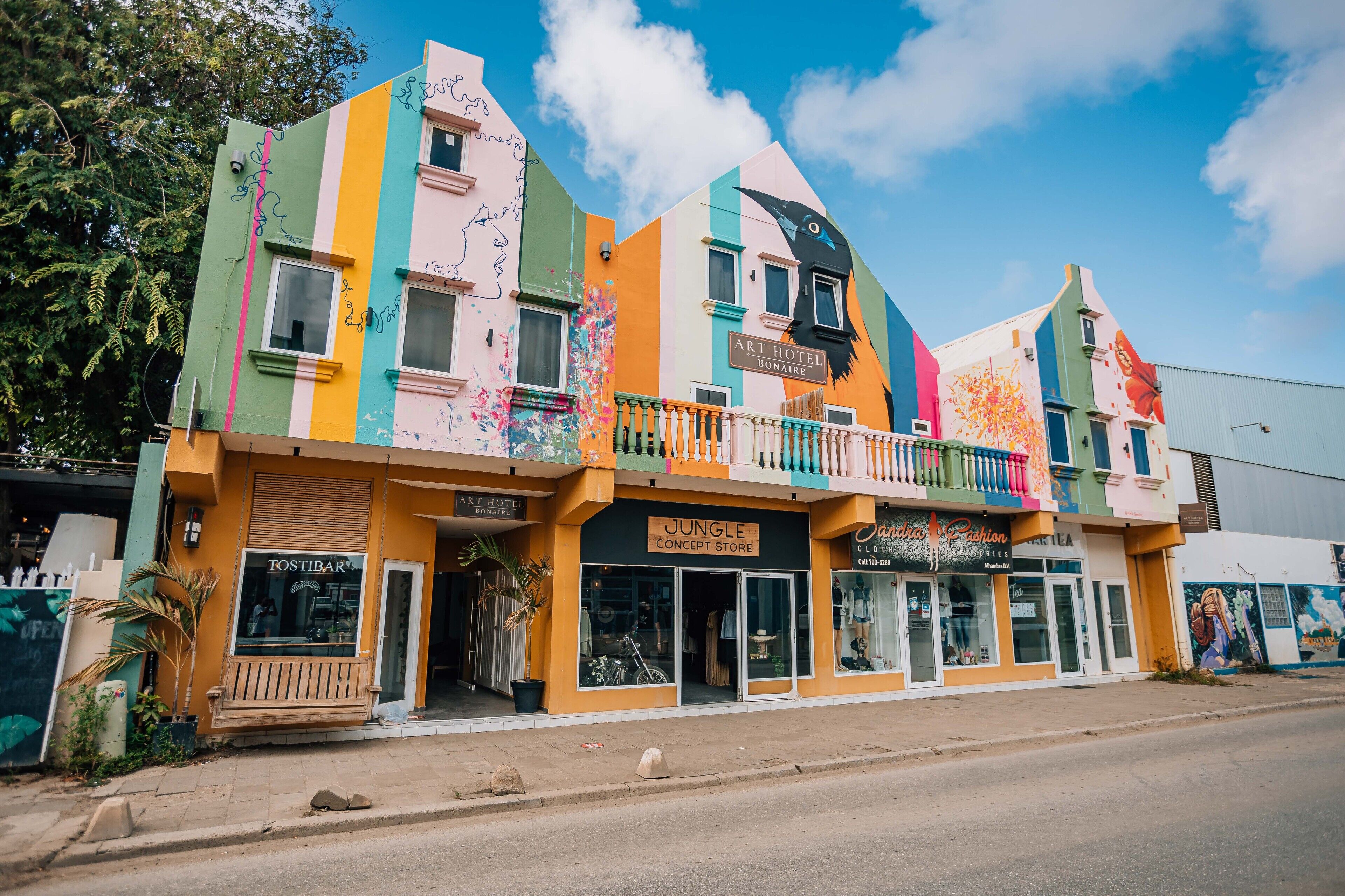 A colorful building with multiple storefronts including Art Hotel Bonaire, Jungle Concept Store, and Jandia Clothing.