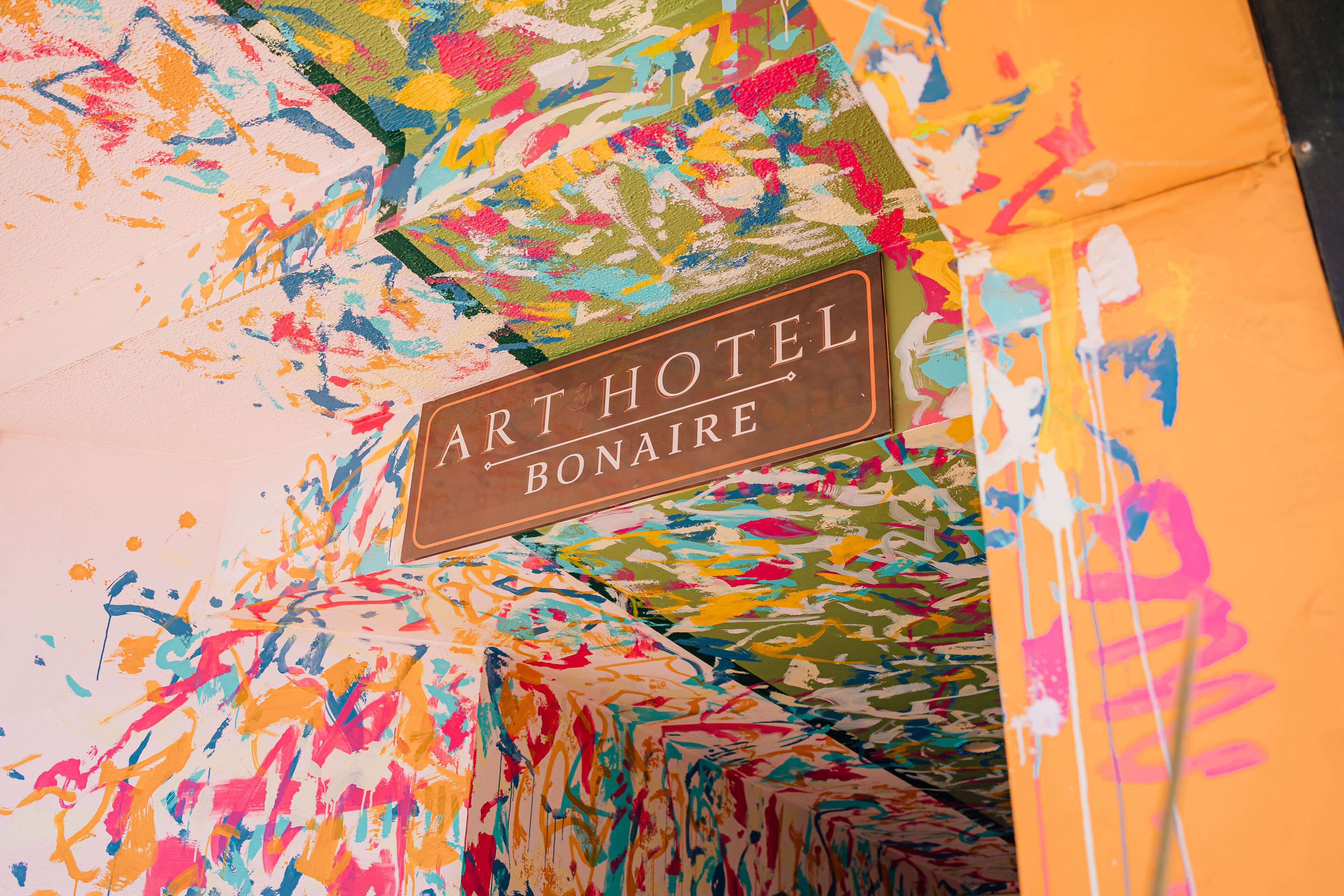 A colorful abstract painting with the text "ART HOTEL BONAIRE" on a brown plaque.