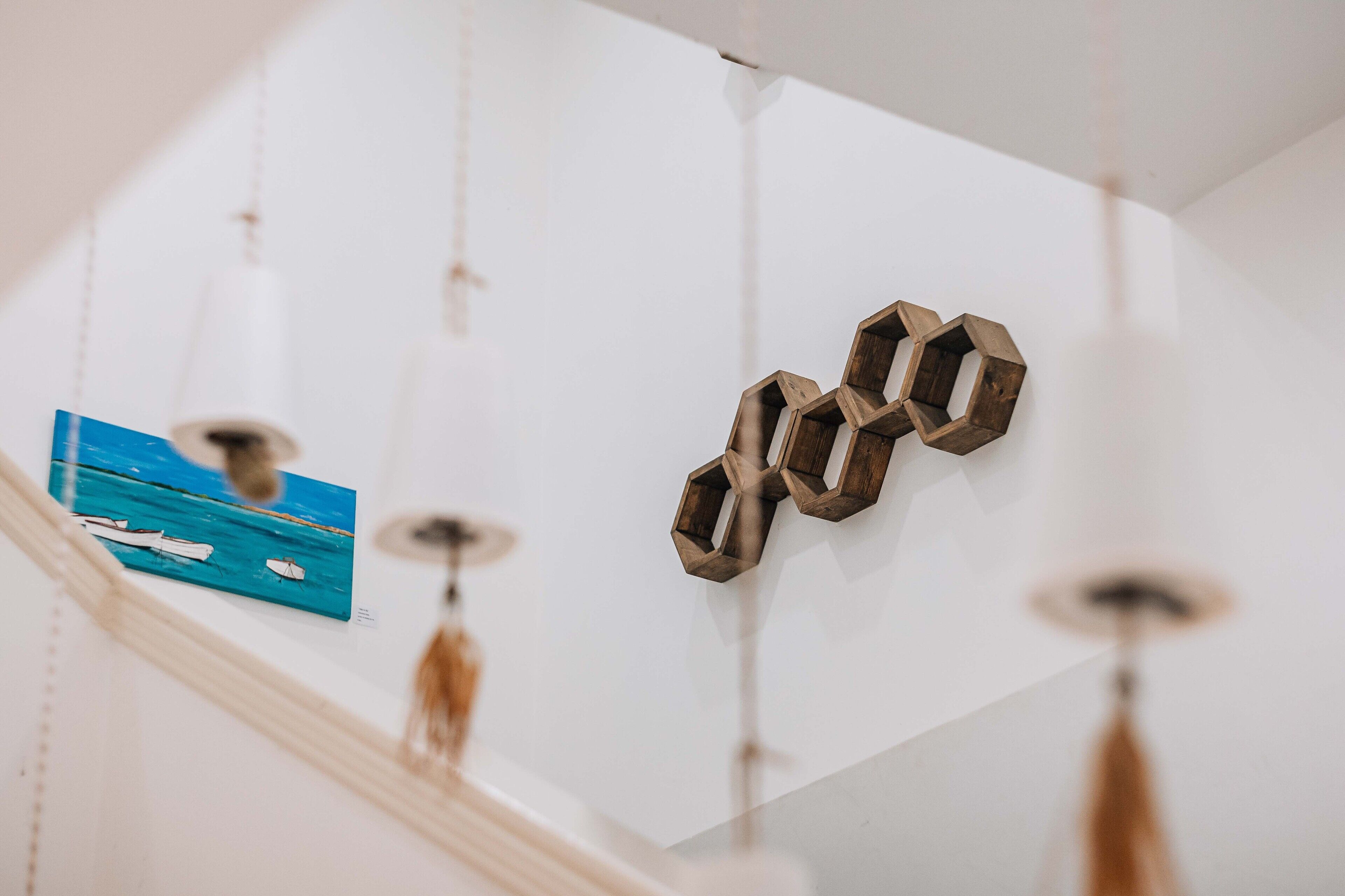 Una habitación con techo blanco, decoración de pared hexagonal de madera y un cuadro azul con barcos.