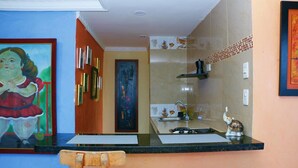 A kitchen with a black countertop, a sink, and a stove. There are two chairs in front of the counter. - Apartment 1c11 Near The Sea With Pool (Cartagena)