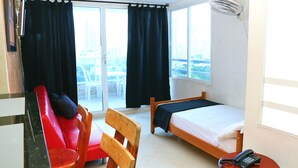 A hotel room with a bed, a chair, a small table with a phone, and a window with curtains. - Apartment 1c11 Near The Sea With Pool (Cartagena)