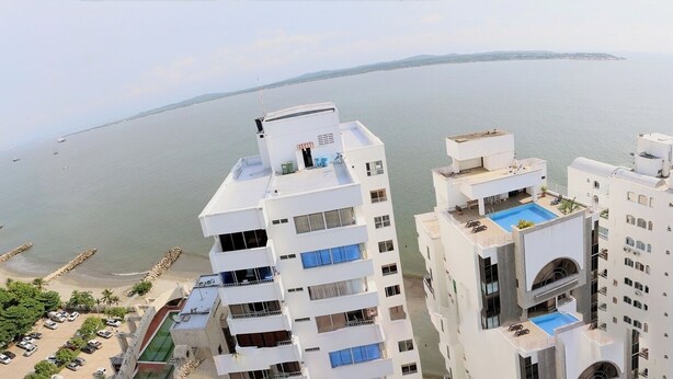 A high-rise hotel with multiple balconies overlooking a beach and the sea.