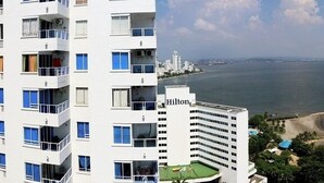 A high-rise hotel with multiple balconies overlooking a coastal area with a beach and a view of the sea. - Apartment 1c19 Close To The Sea With Pool (Cartagena)