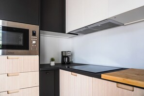 Eine moderne Küche mit Mikrowelle, Kaffeemaschine und Holzschränken.