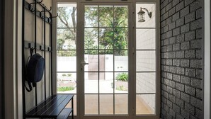 Uma porta com uma estante de metal, um banco e vista para o exterior.