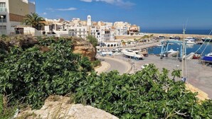 Une ville côtière avec des bâtiments, un port de plaisance et un ciel dégagé.