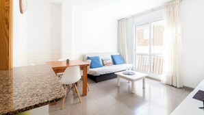 Un salon moderne et bien éclairé, comprenant un canapé, une table basse, une table à manger et une chaise.
