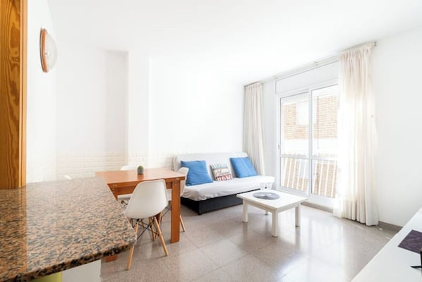 A modern, well-lit living room with a sofa, a coffee table, a dining table, and a chair.