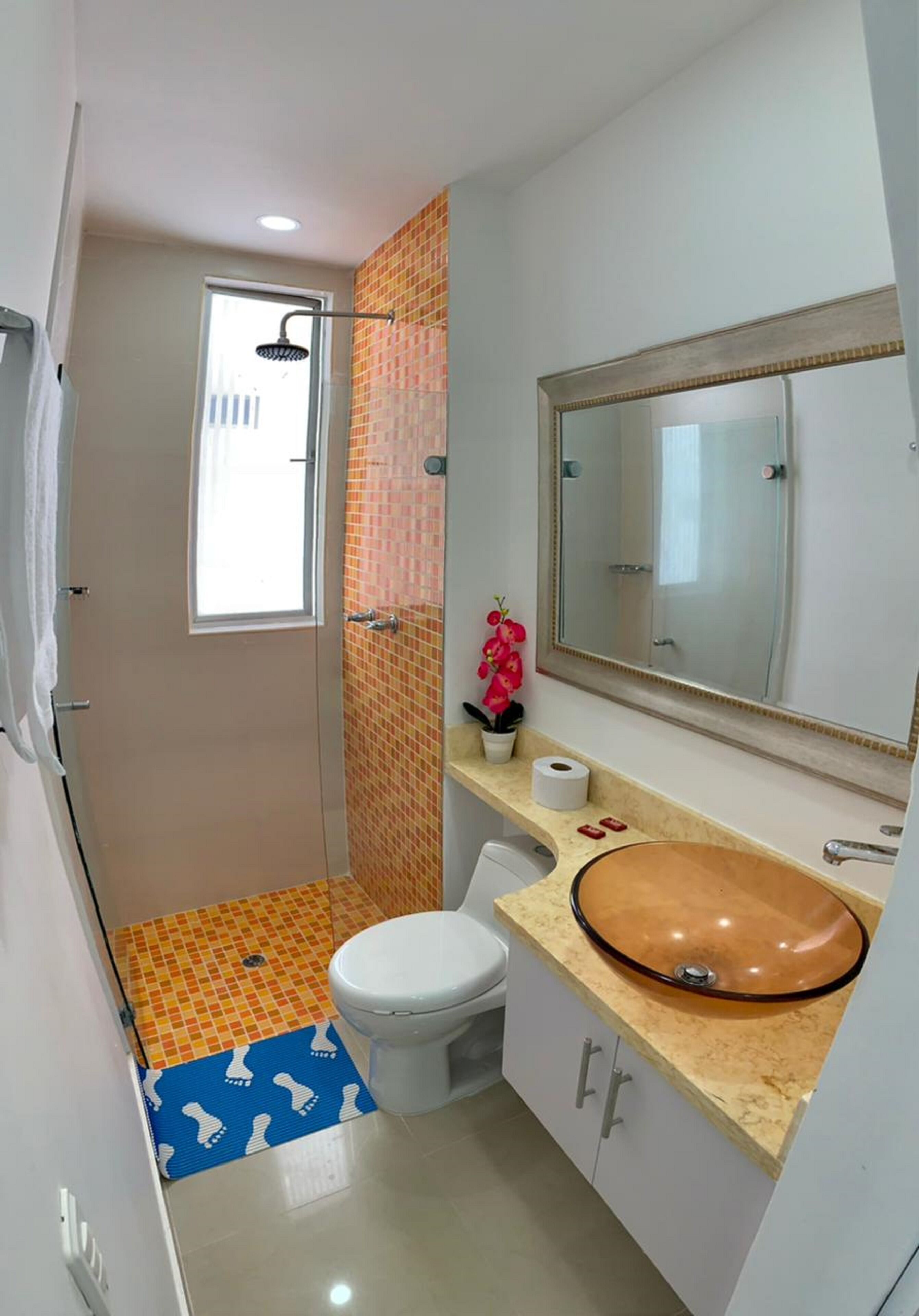 Un baño con ducha, inodoro, lavamanos y espejo.