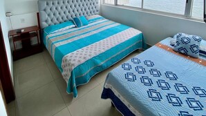 A bedroom with a large window, a tufted headboard, and two beds with striped and patterned bedding. - Apartamento Al-4 Frente al mar Piscina y Wifi (Cartagena)