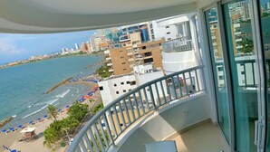 A balcony with a glass railing, a pool, and a table with chairs. - Apartamento Al-4 Frente al mar Piscina y Wifi (Cartagena)