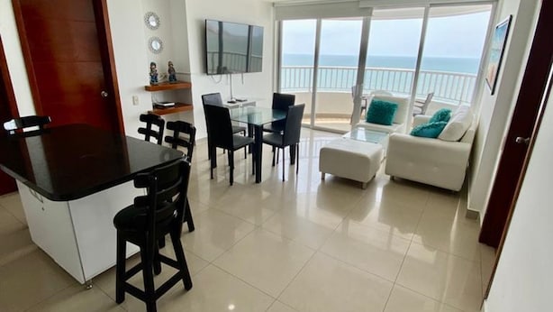 A modern living room with a dining area, a kitchen, and a balcony with a view of the sea. - Apartment Al-1 Facing the sea With Pool and Wifi (Cartagena)