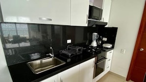 A modern kitchen with white cabinets, a black countertop, a stainless steel sink, a microwave, and an oven. - Apartment Al-1 Facing the sea With Pool and Wifi (Cartagena)