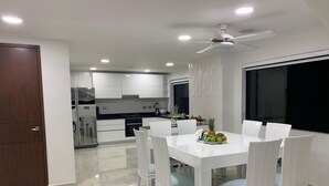 A modern kitchen with white cabinets, a dining table with six chairs, and a ceiling fan. - 3mr8 Duplex Apartment Close To The Sea With Pool (Cartagena)