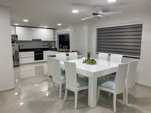 A modern kitchen with white cabinetry, a dining table with six chairs, and a ceiling fan. - 3mr8 Duplex Apartment Close To The Sea With Pool (Cartagena)