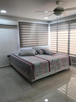 A bedroom with a bed, ceiling fan, air conditioning unit, and large windows with blinds. - 3mr8 Duplex Apartment Close To The Sea With Pool (Cartagena)