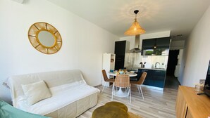 En moderne stue med sofa, et rundt bord og et spiseområde med stole.