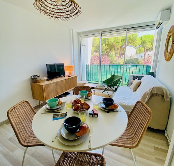 A dining area with a round table, chairs, and a TV on a wooden cabinet.
